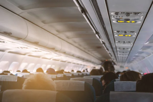 airplane interior with passengers on seats and sunlight effect, shallow depth of field
