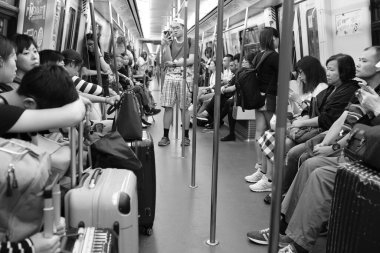 Tanımlanamayan yolcular yoğun saatlerde Hong Kong metro sisteminde akıllı telefonlara bakıyorlar, sığ alan derinliği, siyah beyaz fotoğraf