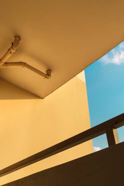 Kanalizasyon boruları ya da güzel mavi gökyüzü olan sarı bina duvarındaki boruları boşaltmak.