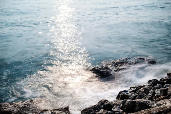 rocks by the sea with beautiful smooth water in sunlight, long exposure photography, old film look effect