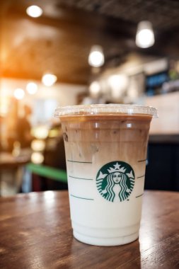 Starbucks buzlu kahve fincanı logolu, en sevdiği buzlu karamelli macchiato kahvesi, dükkanda çekilmiş güzel bir resim ve güneş ışığı efekti.