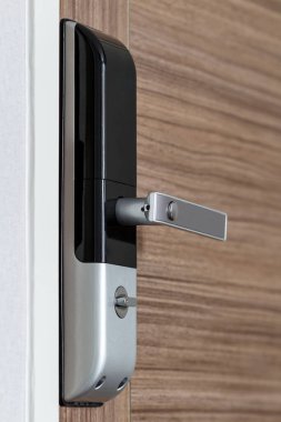 modern electronic door lock with handle on wooden door, security system for condominium or hotel clipart