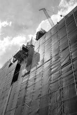 Güneşli bir günde iskele sistemi ve vinçle inşa edilmiş yüksek binalar, siyah beyaz fotoğrafçılık.