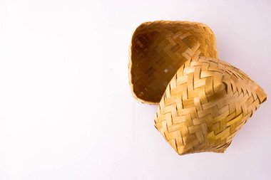 Boş el dokuması bambu hasır kutunun kapağı kısmen beyazın üzerine açılmış. Konteynıra odaklan. Genellikle yiyecek deposu olarak kullanılır..