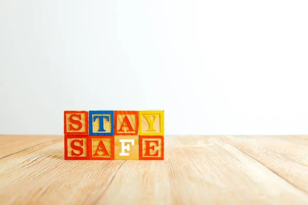 Tahta dokular üzerinde tahta alfabe küpleri. Virüs salgını, kriz ya da acil durum süresince güvende kalma kavramı. Seçici küplere odaklan. Diğer gradyan bulanıklığı.