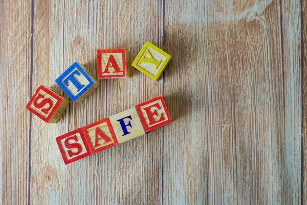 Tahta dokular üzerinde tahta alfabe küpleri. Virüs salgını, kriz ya da acil durum süresince güvende kalma kavramı. Seçici küplere odaklan. Diğer gradyan bulanıklığı.