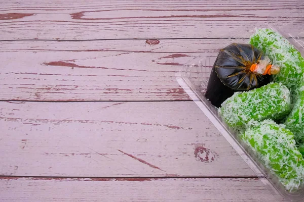 Kuih lopis 'in (pandanda pişirilmiş glutinous rice (screwpine leaves) suyu, hafif tuzlanmış hindistan cevizi talaşı ile kaplanmış palto) yakın çekimi. Kahverengi şeker şurubuyla servis edilmiş. Seçici odak.