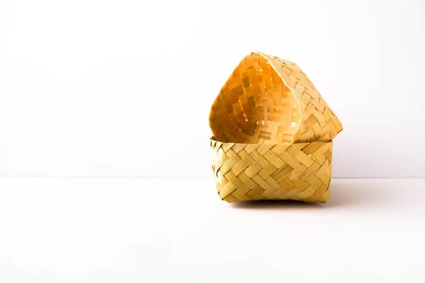 Küçük boş el dokuması bambu hasır kaplama kabı beyazın üzerine yan yerleştirilmiş. Konteynıra odaklan. Genellikle yiyecek deposu olarak kullanılır..