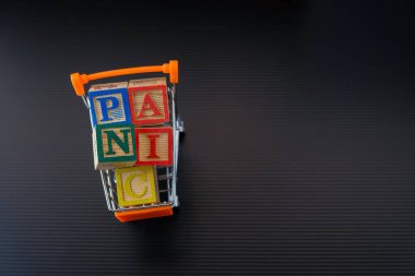 Virüs salgını sırasında yiyecek ya da market alışverişi ya da ciddi kriz kavramı. Tahta küpler, karanlık ve tozlu yüzeyde mini tramvayda aşırı yüklendi. Seçici küplerin odağı.