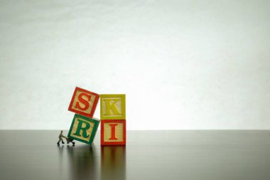 RISK mesajlı harf bloğu. Risk ve belirsizliğin kavramsal görüntüsü. Minyatür işçi tarafından kaldırılan izole ahşap bloklar. S harfine odaklan.