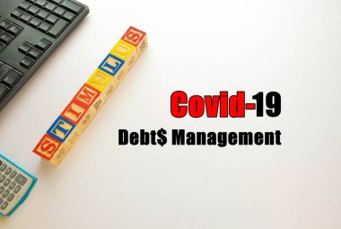 Kriz sırasında veya Covid-19 sırasında hükümetin ekonomik uyarıcı paketlerinden gelen kavramsal borç yönetimi. Hesap makinesi klavyesinin üst görünümü ve beyaz harf blokları. Metinlere seçici odaklanma.
