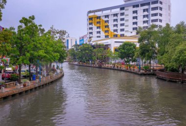 Malacca City, Malezya - 2019 Aralık 19: Yaya geçidi, nehir kenarındaki yenilenmiş binalar ve mavi gökyüzü ile güzel bir Malacca nehri. Nehir yolculuğu rotası. Önplanda seçmeli odak.