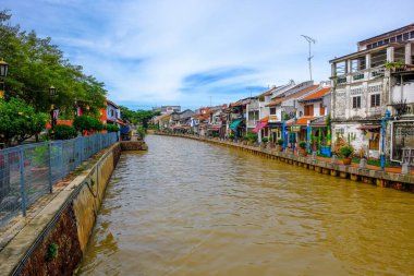 Malacca City, Malezya - 2019 Aralık 19: Yaya geçidi, nehir kenarındaki yenilenmiş binalar ve mavi gökyüzü ile güzel bir Malacca nehri. Nehir yolculuğu rotası. Önplanda seçmeli odak.