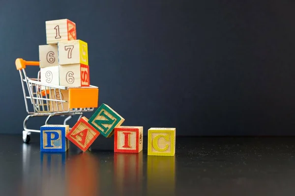 Virüs salgını sırasında yiyecek ya da market alışverişi ya da ciddi kriz kavramı. Tahta küpler, karanlık ve tozlu yüzeyde mini tramvayda aşırı yüklendi. Seçici küplerin odağı.