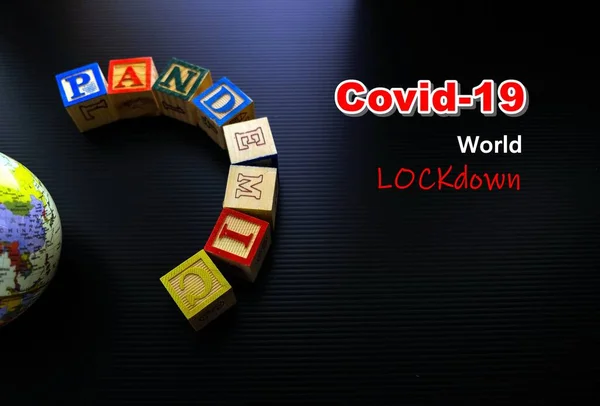 WHO ve dünya karantinası tarafından ilan edilen covid-19 salgını kavramı. Gösterişsiz görüntü. Karanlık yüzeyde tahta alfabe küpleri ve kısmen düzenlenebilir metinleri olan dünya kübü. Sadece seçici küplere odaklan.