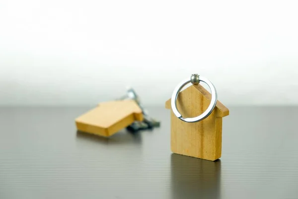 İpotek kavramı ve ev sahipliği. Sağdaki masada izole edilmiş ahşap anahtarlıklar..
