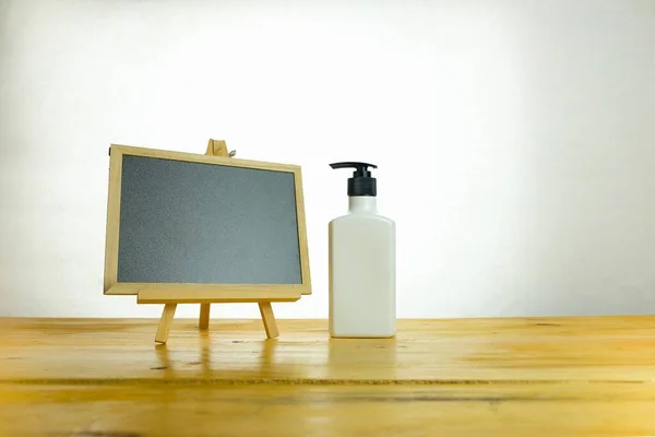 Koronavirüs salgını sırasında hijyenik kalma kavramı. Tahta masada el dezenfektanı ve karatahta izole edilmiş. Sadece tahtaya odaklan..