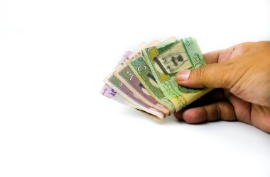 Suudi riyal notlarını SR1, SR5, SR50 ve SR 100 bölü beyaz olarak tutan bir adamın görüntüsü. Sadece SR1 merkezine odaklan.