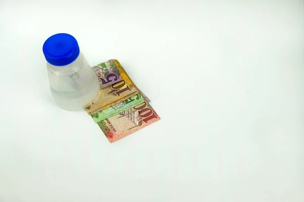 Plastik şişenin altında SAR5, 10, 50 ve 100 'lük banknotlar halinde Suudi riyal banknotlarının ayrı bir görüntüsü var. SAR 100 notlarına odaklan .
