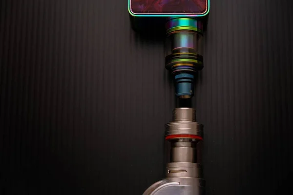 Son zamanlarda e-sigaranın sağlık güvenliğinin belirsizliği kavramı. Ağızlığa ve bataryaya bağlı 2 adet buharlaştırma seti koyu yüzey üzerinde..