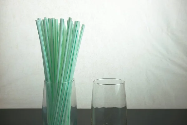 玻璃外侧面的塑料吸管 世界概念的问题是一次性塑料对可重复使用的钢秸秆 以稻草为中心的选择性焦点 — 图库照片