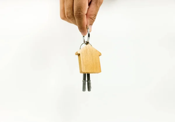 Ev anahtarlarının kavramsal görüntüsü ev finansmanı sürecini tamamladıktan sonra devredilir. Ev şeklindeki ahşap anahtarlık parmaklarda. Mesajlar için boşluk. Tahta tuşlara odaklan; diğeri gradyan bulanıklığına.