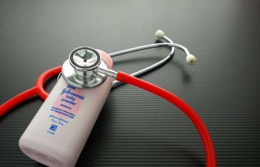 Kuala Lumpur Malaysia-Nov 10 2019: Kırmızı steteskop Johnson 'ın bebek pudrası kutusunu yukarı bakan logoyla inceliyor. Çan diyaframı kısmına odaklan. ABD FDA 'nın en son asbest içeriği kaygısı.