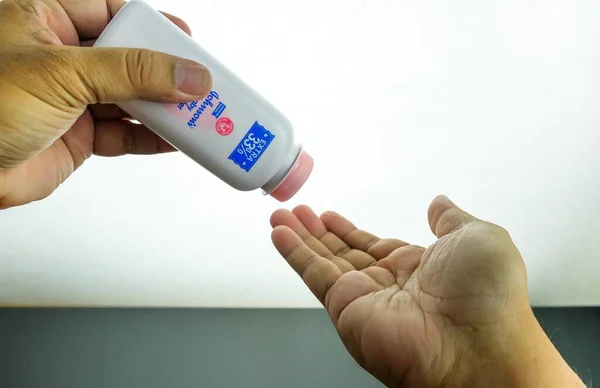 Kuala Lumpur Malezya-Nov 10 2019: Johnson 'ın konteynırı eline bebek pudrası dökmek üzere. Ekstra% 33 'lük metinlere odaklan. ABD FDA 'nın en son asbest içeriği kaygısı.