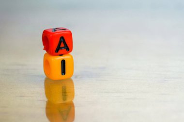 Gelecekteki bilişim teknolojilerinde yapay zeka kavramı. Yansıtıcı yüzeyde birbirinden izole edilmiş iki renkli alfabe boncuğu. Boncuklara odaklan. Diğer gradyan bulanıklığı.