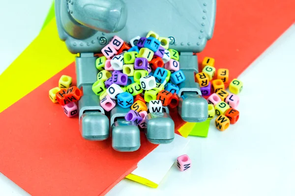 Kavramsal makine öğrenmesi. Robot el alfabe boncuklarıyla makineyi temsil ediyor. Yansıtıcı yüzey. Merkezdeki boncuğa odaklan. Resim biraz gürültü ve yumuşak odak içerir.