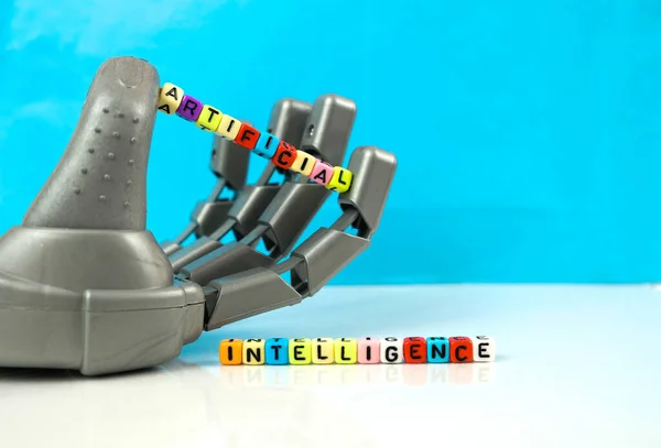  Robot pençeli el, yansıtıcı yüzeyde düzenlenmiş alfabe boncuklarını tutan makineyi sembolize ediyor. Robot elinin merkezindeki boncuklara odaklan. Kavramsal yapay zeka..