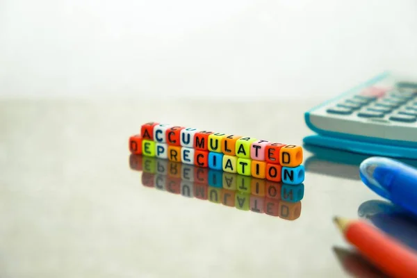 Conceptual of accumulated depreciation in financial statements.  Focus on text on beads at front.Colorful alphabet beads stacked forming the words over reflective table.
