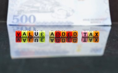 Suudi Arabistan 'da kavramsal değer katma vergisi. Yansıtıcı karanlık yüzeye yansıyan koloful alfabe boncuklarına katma değer vergisi. Boncuklara odaklan; Suudi riyal notu da dahil olmak üzere bulanık içindeki diğerleri.
