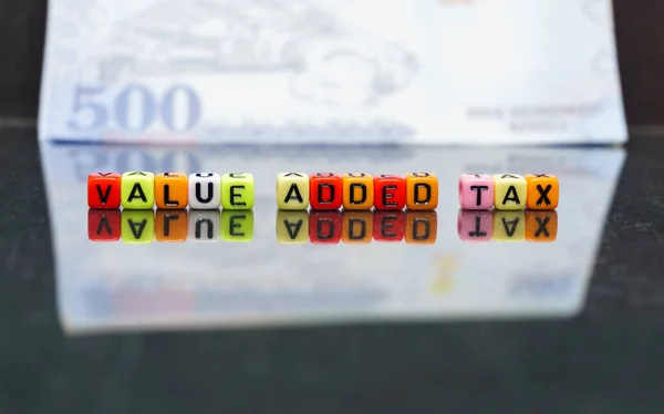 Suudi Arabistan 'da kavramsal değer katma vergisi. Yansıtıcı karanlık yüzeye yansıyan koloful alfabe boncuklarına katma değer vergisi. Boncuklara odaklan; Suudi riyal notu da dahil olmak üzere bulanık içindeki diğerleri.