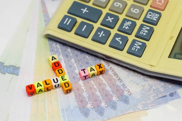 Suudi Arabistan 'da kavramsal değer katma vergisi. Coloful alfabe boncuklarına katma değer vergisi. Boncuklara odaklan; Suudi riyal notu da dahil olmak üzere bulanık içindeki diğerleri.