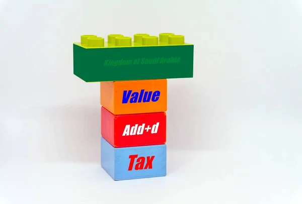 Conceptual of value-added tax roll-out in Saudi Arabia. Stacked colorful plastic bricks with texts value added tax and kingdom of saudi arabia on green color of Saudi Arabia flag.