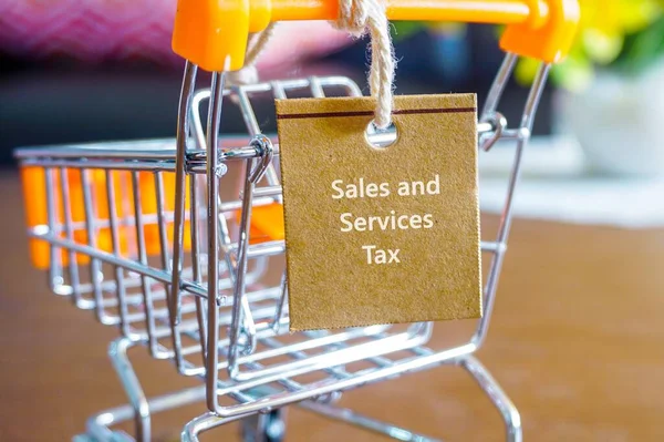 Açık kahverengi etiketli beyaz metinler mini tramvay çizelgesine bağlanmış. Malezya 'daki Satış ve Hizmetler Vergisinin kavramsal görüntüsü. Kahverengi etikete odaklan. Diğer gradyan bulanıklığı.