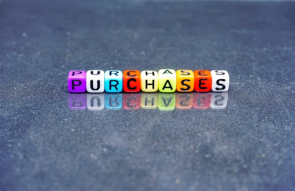 Conceptual of purchases, profit and loss item in financial statements. Texts on colorful beads on dark reflective table. Focus on selective beads. Others in gradient blur. Dark background.