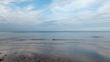 Deniz manzarasında, sonbaharın erken saatlerinin güzel akşam gökyüzünün altında pürüzsüz bir deniz yüzeyi vardır. Küçük bir dalga kumlu sahilde yuvarlanır, rahatlar. ...