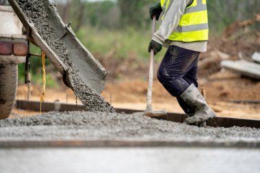 İnşaat işçisi inşaat alanına beton döküyor.