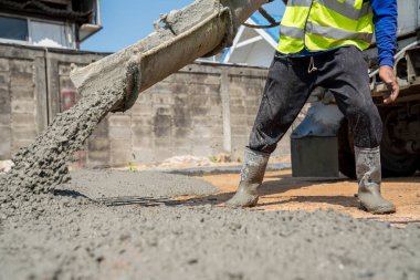 İnşaat işçisi inşaat alanına beton döküyor.
