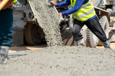 İnşaat işçisi inşaat alanına beton döküyor.