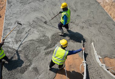 İnşaat işçisi inşaat alanına beton döküyor.