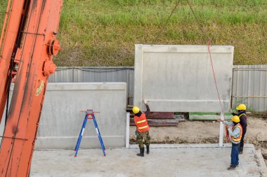 İnşaat işçisi ve mühendis taşınabilir vinç arıyor. Yeni inşaat deposunun inşaat sahasında kaldırma öncesi beton duvar.