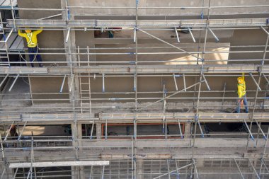 Üst düzey inşaat işçileri beton alçı karışımı çimento kullanarak inşaat duvarlarını sıvadılar.