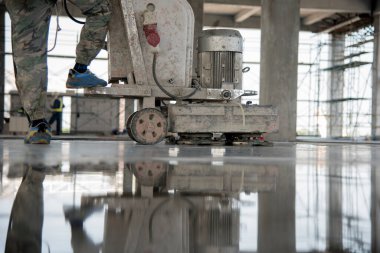 İnşaat işçisi harcı üretir ve özel bir aletle ıslak betonu bitirir. Yüzen bıçaklar. Betonu düzleştirmek ve cilalamak için, beton zemin