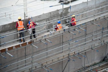 İnşaat alanına beton su tankı yapıştıran bir grup inşaat işçisi.