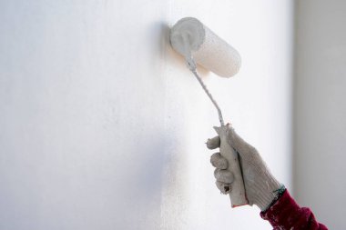 Yeni beton duvardaki inşaat işçisinden boyacı.