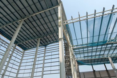Çelik kiriş ve metal çatı inşaat sahasında çalışıyor.