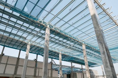 Çelik kiriş ve metal çatı inşaat sahasında çalışıyor.